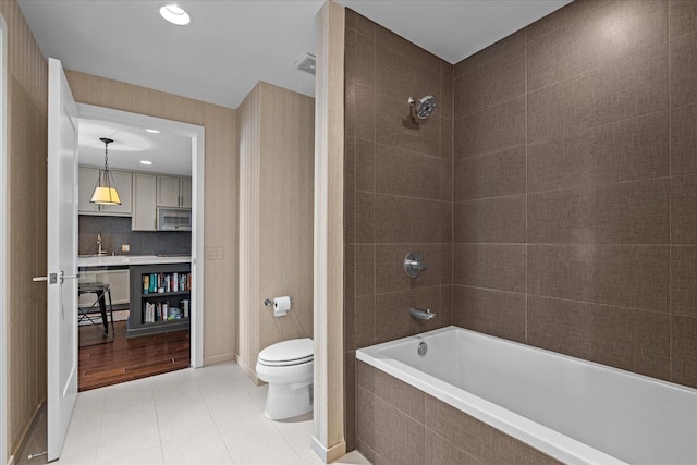 full bathroom featuring tile patterned flooring, toilet, a sink, visible vents, and tiled shower / bath