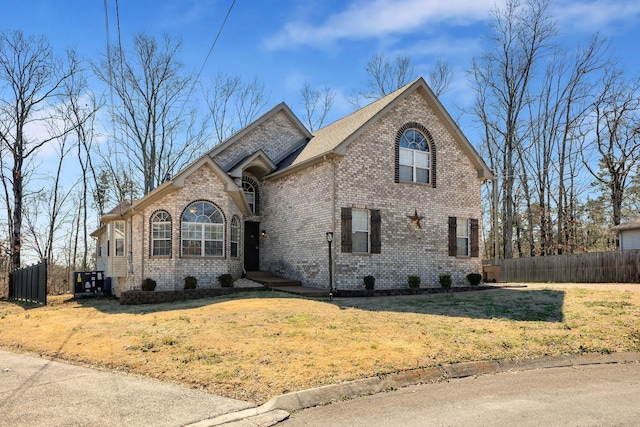 french country style house with brick siding, a front lawn, and fence