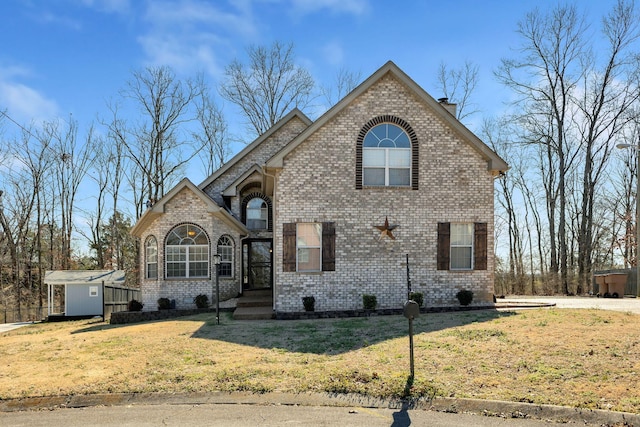 view of front of house featuring a storage shed, brick siding, a chimney, an outbuilding, and a front yard