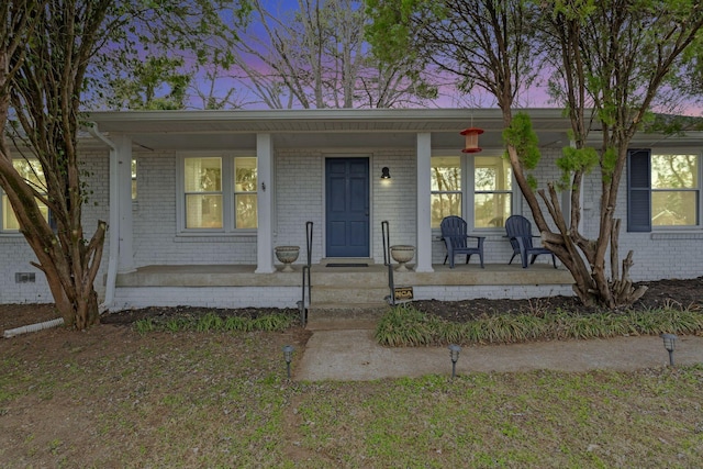 view of front of home with a porch and brick siding