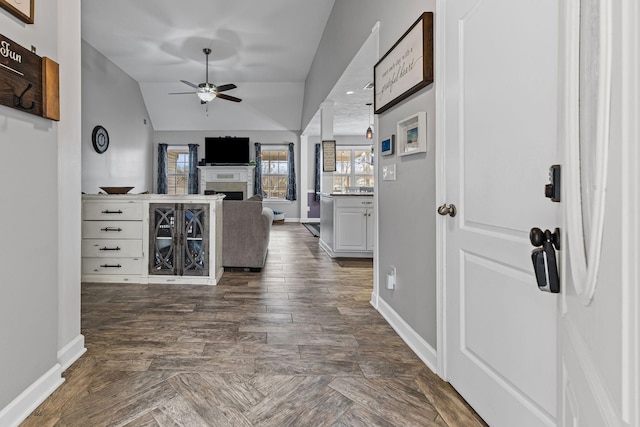 hallway with lofted ceiling, baseboards, and dark wood-type flooring