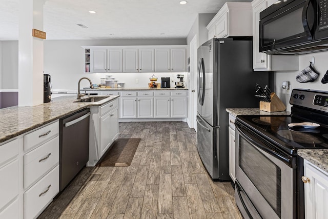 kitchen featuring light stone counters, appliances with stainless steel finishes, light wood-style floors, white cabinets, and a sink