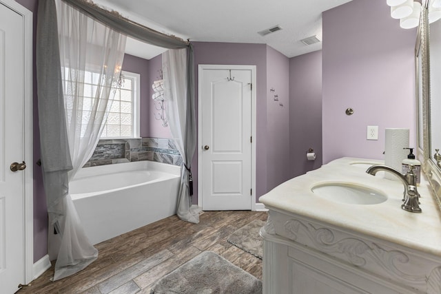 full bathroom featuring a sink, visible vents, wood finished floors, and a bath