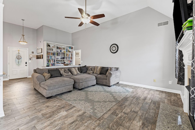 living area with visible vents, baseboards, ceiling fan, wood finished floors, and high vaulted ceiling