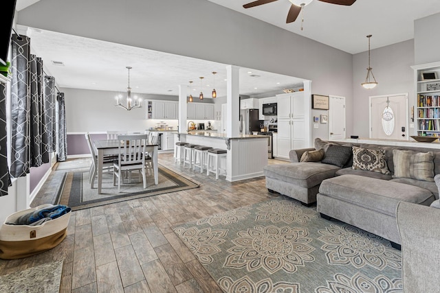 living area with recessed lighting, baseboards, wood finished floors, and ceiling fan with notable chandelier