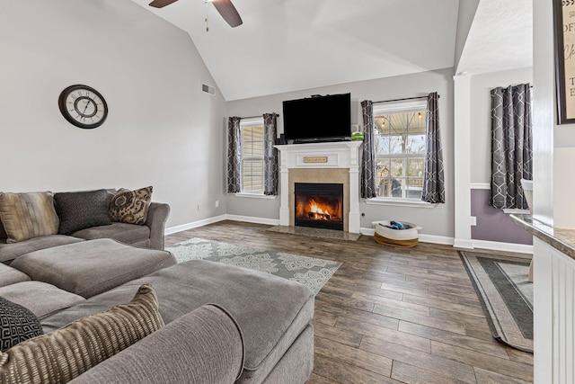 living room featuring visible vents, a lit fireplace, baseboards, and wood finished floors