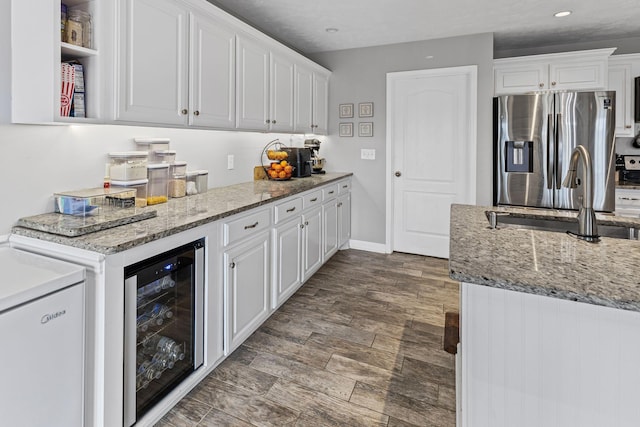 kitchen featuring beverage cooler, stainless steel fridge, a sink, and white cabinetry