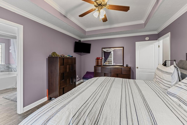 bedroom featuring baseboards, a tray ceiling, wood finished floors, and crown molding