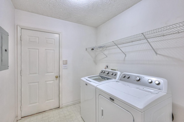 clothes washing area with laundry area, washing machine and dryer, light floors, and a textured ceiling