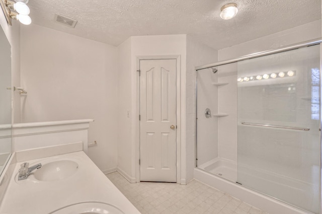 full bath with a textured ceiling, a sink, visible vents, tile patterned floors, and a stall shower