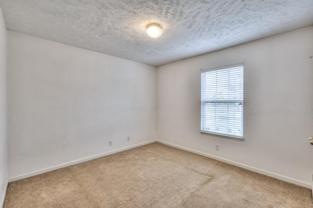 carpeted empty room with baseboards and a textured ceiling