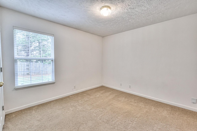 carpeted spare room with baseboards and a textured ceiling