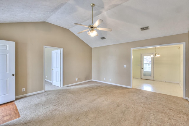 carpeted empty room with vaulted ceiling, ceiling fan with notable chandelier, visible vents, and baseboards