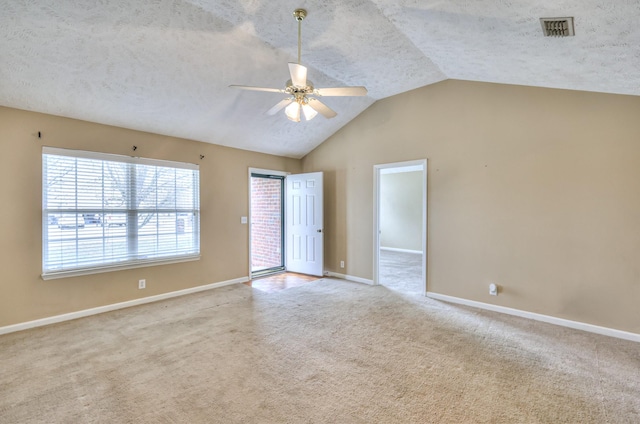 carpeted spare room featuring visible vents, vaulted ceiling, ceiling fan, a textured ceiling, and baseboards