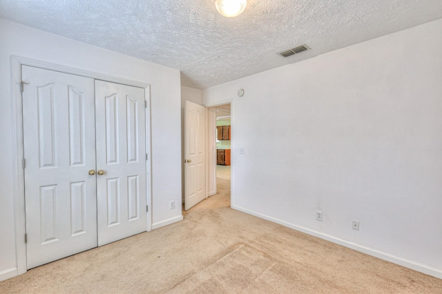 unfurnished bedroom with carpet, a closet, visible vents, a textured ceiling, and baseboards