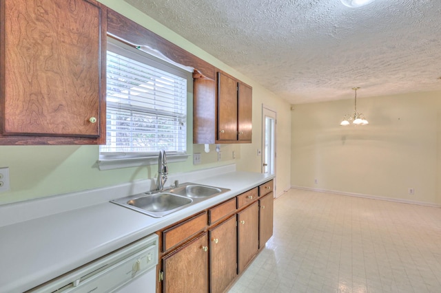 kitchen with brown cabinetry, an inviting chandelier, white dishwasher, light countertops, and a sink