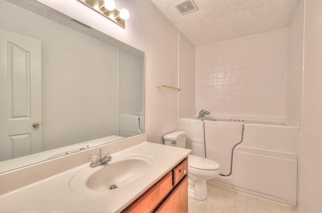 bathroom with visible vents, toilet, a bathtub, a textured ceiling, and vanity