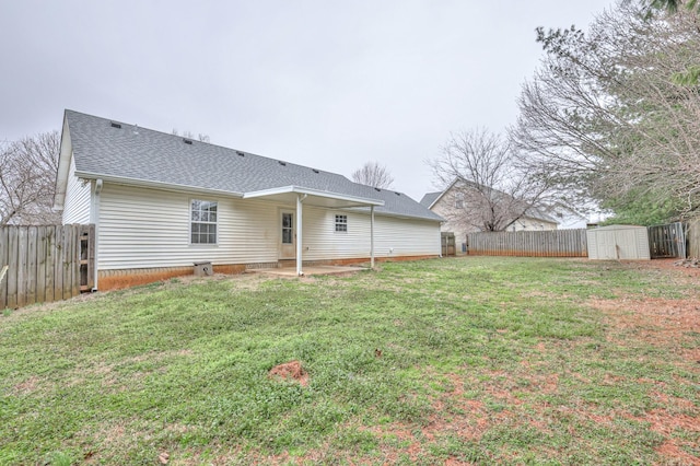 rear view of house featuring roof with shingles, a yard, a storage unit, a fenced backyard, and an outdoor structure