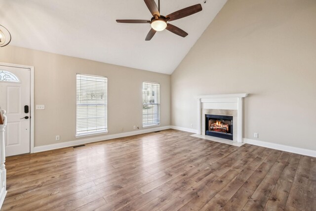 unfurnished living room with baseboards, visible vents, ceiling fan, wood finished floors, and a fireplace