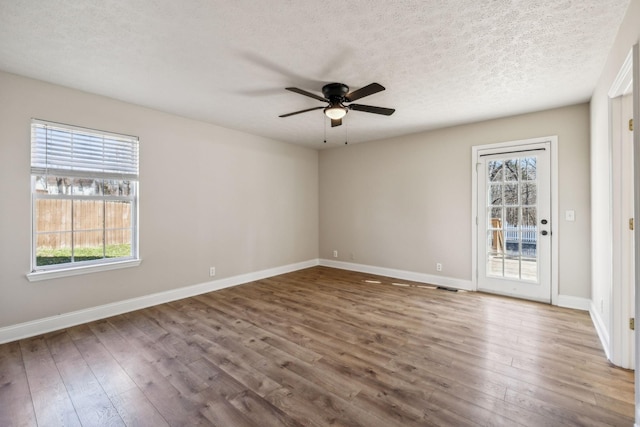 unfurnished room with ceiling fan, a textured ceiling, baseboards, and wood finished floors