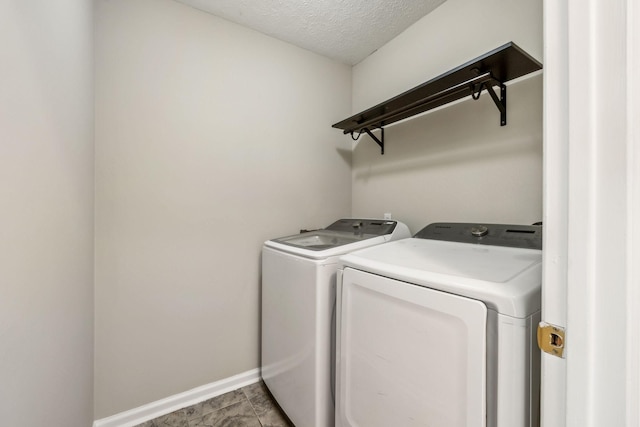 laundry area featuring laundry area, baseboards, a textured ceiling, and washing machine and clothes dryer