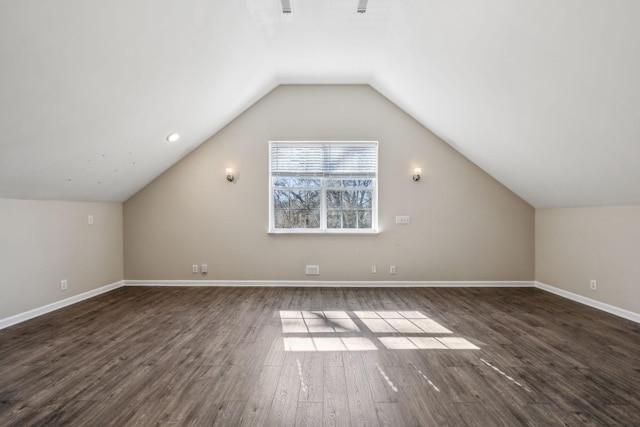 additional living space featuring dark wood-type flooring, vaulted ceiling, and baseboards