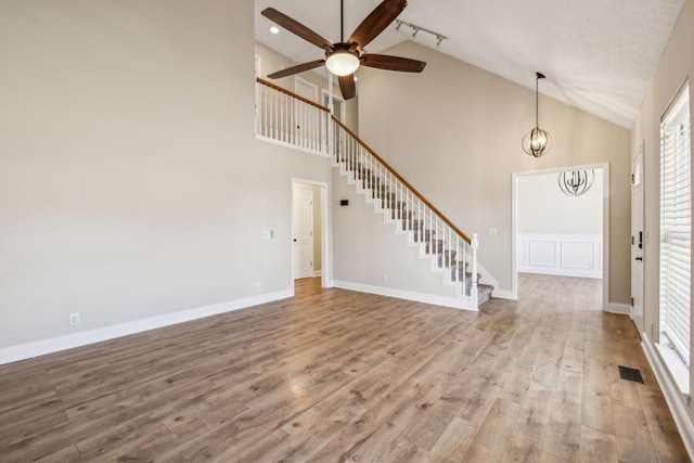 interior space featuring baseboards, visible vents, stairway, wood finished floors, and ceiling fan with notable chandelier