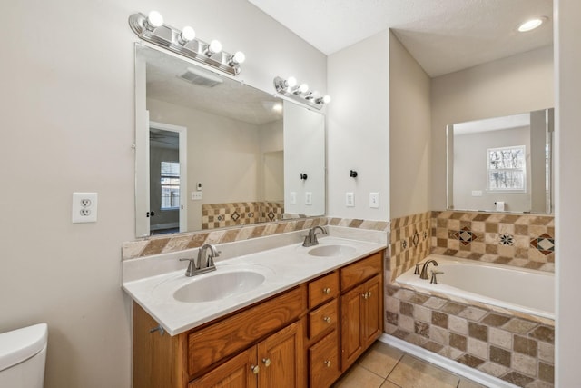 bathroom with tile patterned flooring, a garden tub, a sink, and toilet