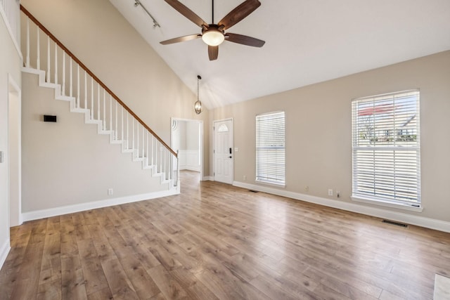 interior space with baseboards, visible vents, wood finished floors, stairs, and high vaulted ceiling