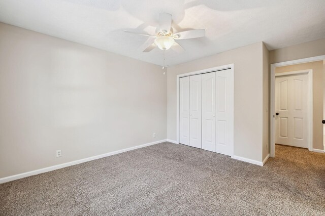 unfurnished bedroom with carpet, baseboards, ceiling fan, and a closet