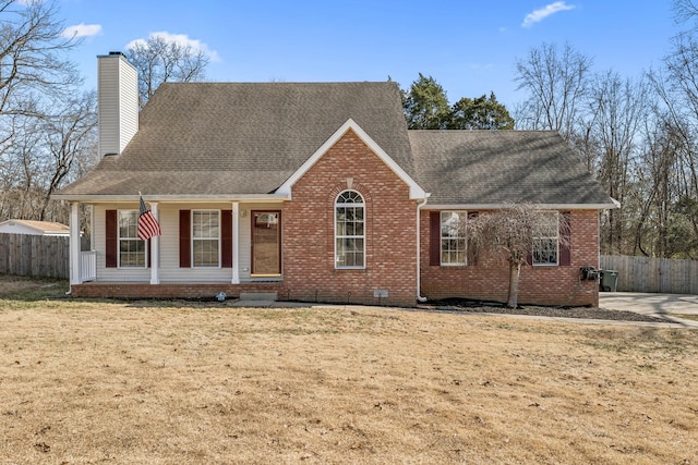 view of front of home featuring brick siding, a chimney, a front yard, and fence