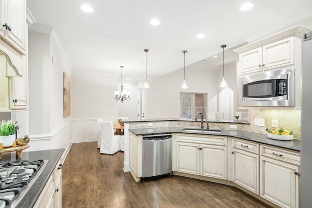 kitchen featuring a wainscoted wall, dark wood finished floors, crown molding, stainless steel appliances, and a sink