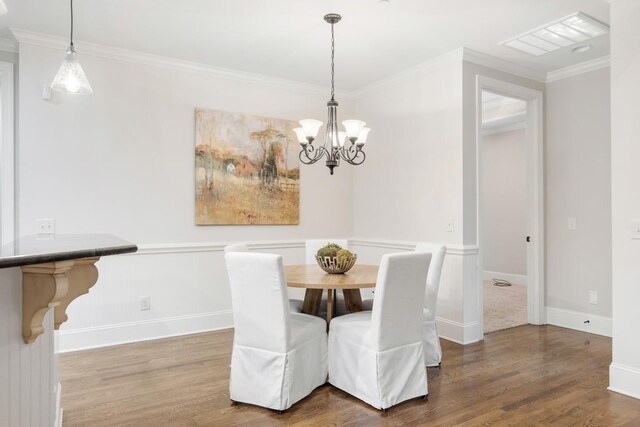 dining space featuring baseboards, a notable chandelier, ornamental molding, and wood finished floors