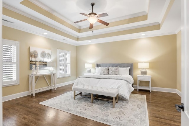 bedroom with visible vents, multiple windows, a tray ceiling, and wood finished floors