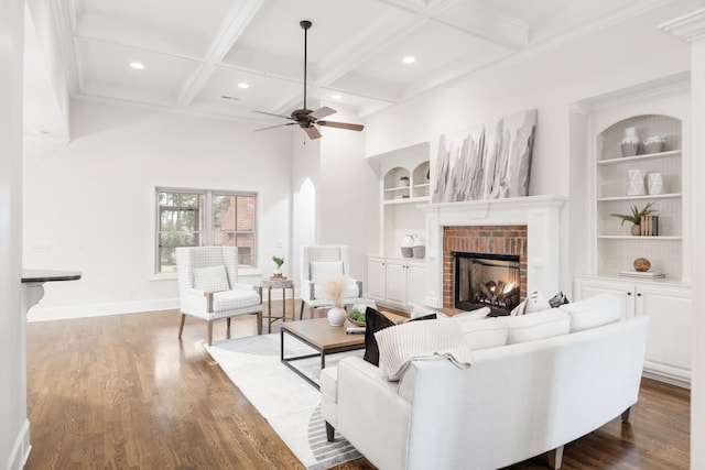 living room with built in features, a brick fireplace, coffered ceiling, and dark wood finished floors