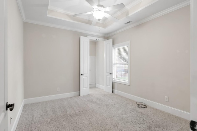 unfurnished room with baseboards, visible vents, a tray ceiling, crown molding, and carpet floors