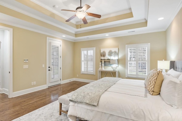 bedroom featuring baseboards, a raised ceiling, ornamental molding, wood finished floors, and recessed lighting