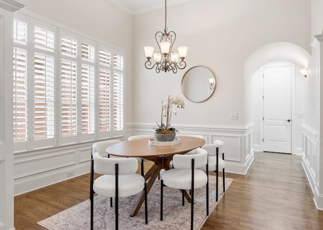 dining area featuring a notable chandelier, a wainscoted wall, wood finished floors, and a decorative wall