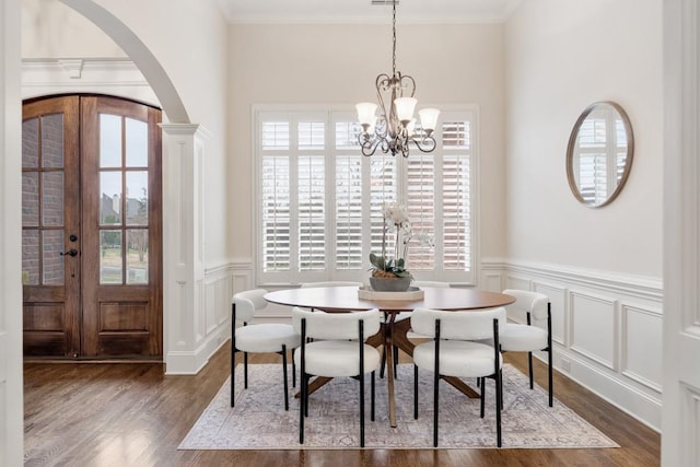 dining area featuring arched walkways, dark wood-style flooring, french doors, an inviting chandelier, and crown molding