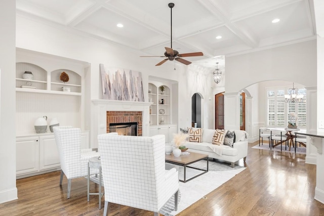 living area with coffered ceiling, a fireplace, wood finished floors, and built in features