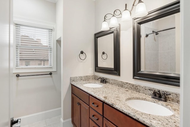 full bathroom with double vanity, tile patterned flooring, a sink, and baseboards