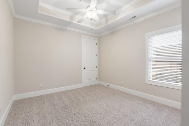 empty room with visible vents, a raised ceiling, baseboards, carpet, and crown molding