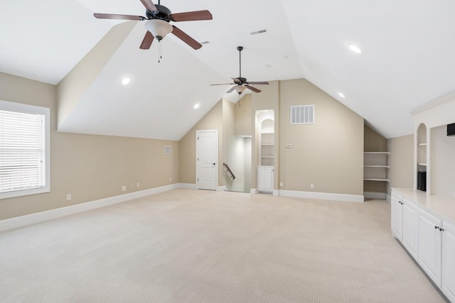 unfurnished living room with built in features, light colored carpet, visible vents, vaulted ceiling, and baseboards