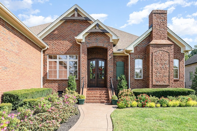 doorway to property with french doors, a chimney, and brick siding