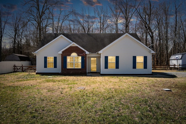 ranch-style house featuring a yard, brick siding, and fence