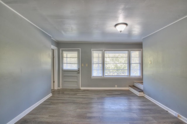 unfurnished room featuring stairway, plenty of natural light, baseboards, and wood finished floors