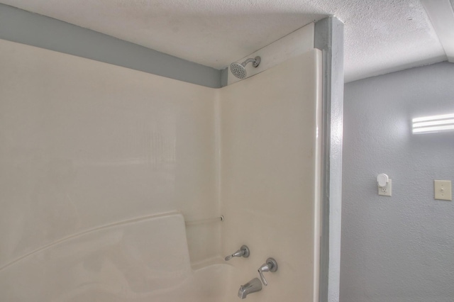 interior details with a textured ceiling and shower / bathing tub combination