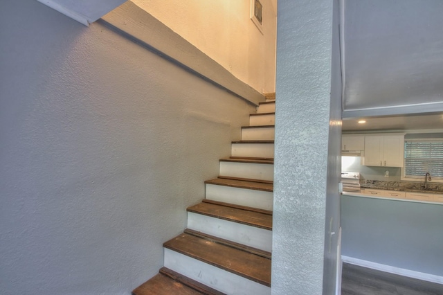 stairs featuring a textured wall and wood finished floors