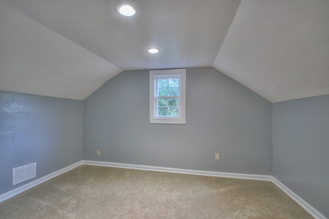 additional living space featuring carpet flooring, visible vents, vaulted ceiling, and baseboards