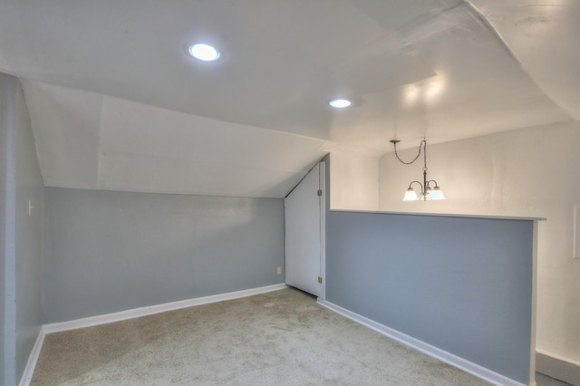 bonus room featuring light carpet, an inviting chandelier, baseboards, and vaulted ceiling